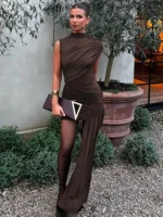 Woman in elegant brown dress with asymmetrical design and sheer legging detail.