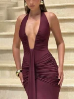 Woman in elegant burgundy dress with deep neckline and ruched design.