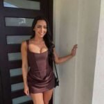 Elegant woman in a brown dress standing outside Thrive Store, showcasing fashion and confidence.