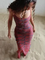 Red and black tiger print maxi dress on woman standing on sandy surface.