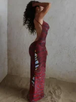 Elegant woman in stylish tiger print jumpsuit, standing against textured wall on sandy floor.