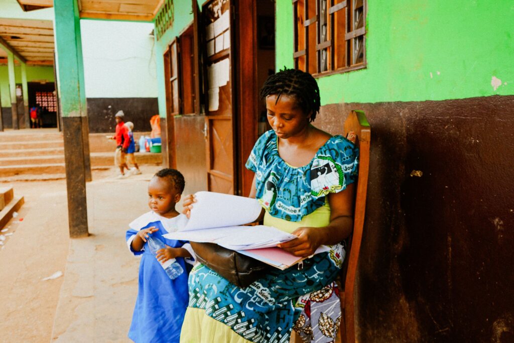 A woman in a wheelchair reads with a young child in a classroom doorway